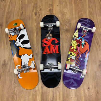 3 Skateboards on the floor. The Brand Scam Skate is in the middle