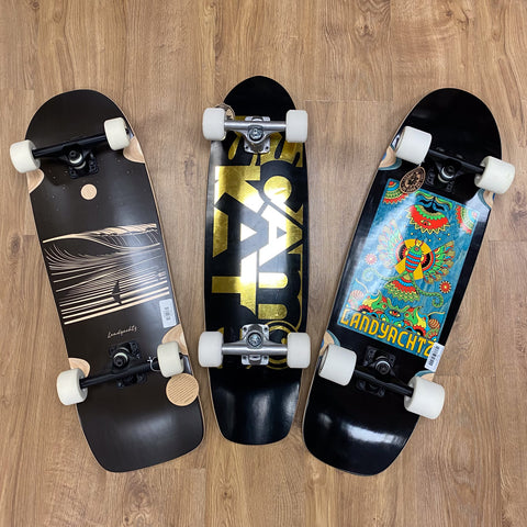3 Cruiser boards on the floor. The brand Scam Skate is in the middle